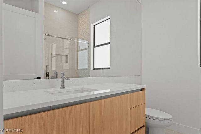 bathroom with a stall shower, vanity, toilet, and recessed lighting