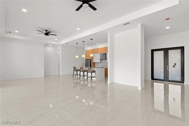 living area with ceiling fan, recessed lighting, french doors, a raised ceiling, and light tile patterned floors