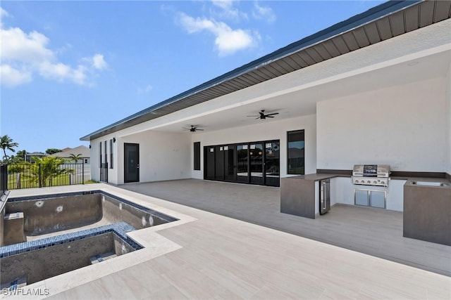 view of pool featuring an outdoor kitchen, a ceiling fan, fence, a patio area, and grilling area