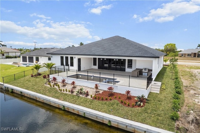 back of property with stucco siding, a shingled roof, a water view, and a patio area