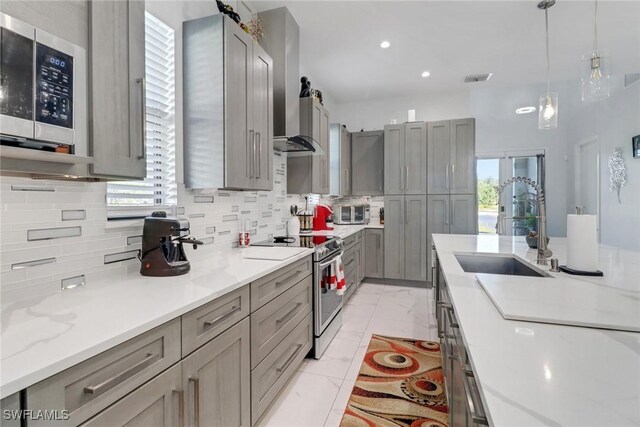 kitchen featuring tasteful backsplash, a sink, gray cabinets, decorative light fixtures, and appliances with stainless steel finishes
