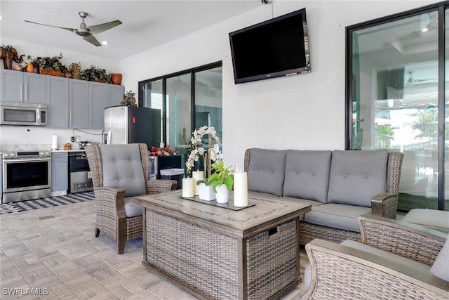 view of patio featuring ceiling fan, an outdoor living space, and exterior kitchen