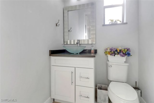 bathroom featuring baseboards, vanity, and toilet