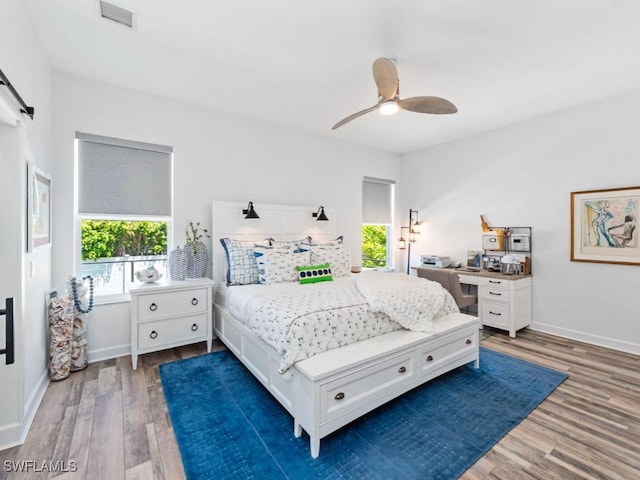bedroom featuring visible vents, baseboards, a ceiling fan, and wood finished floors
