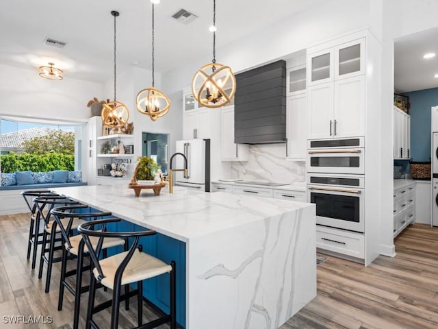 kitchen featuring decorative backsplash, white cabinetry, a chandelier, and white appliances