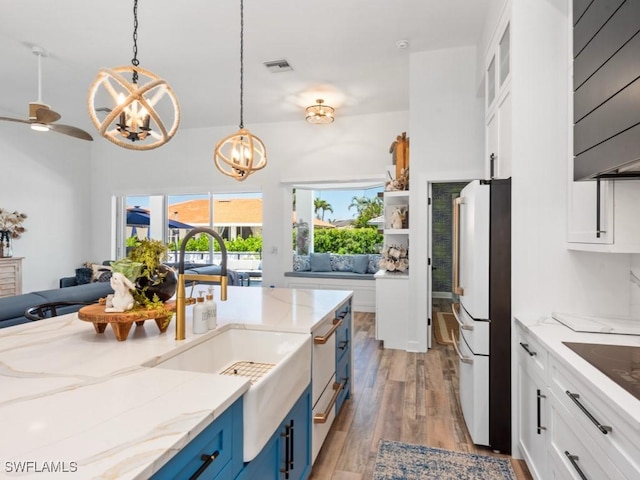 kitchen with freestanding refrigerator, visible vents, blue cabinetry, and white cabinetry