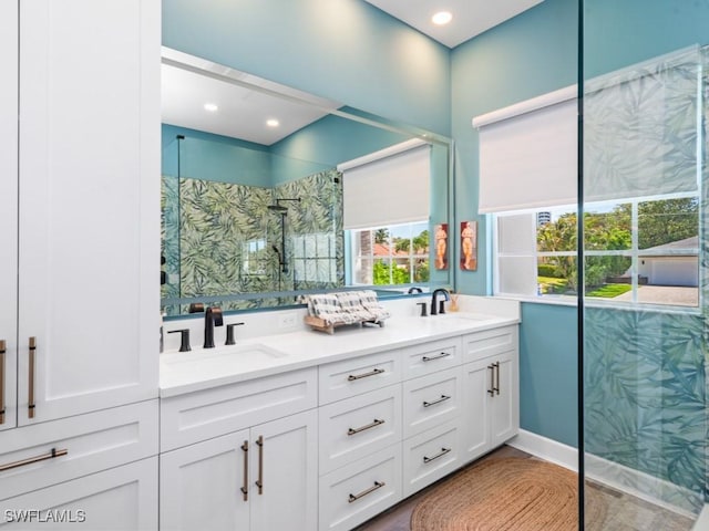bathroom with a shower with door, a sink, double vanity, and recessed lighting