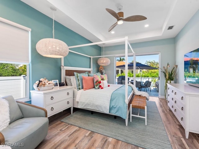 bedroom with recessed lighting, a raised ceiling, wood finished floors, access to exterior, and visible vents