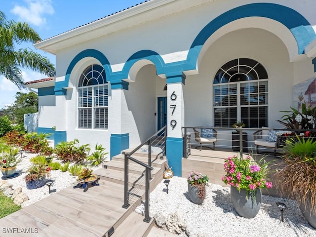 property entrance featuring covered porch and stucco siding