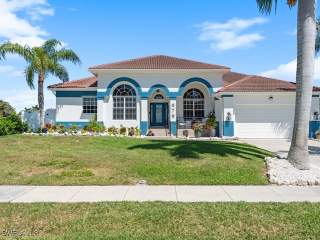 mediterranean / spanish-style home featuring a tile roof, driveway, an attached garage, a front yard, and stucco siding