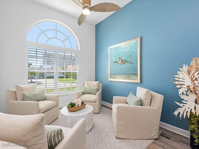 living area featuring wood finished floors, baseboards, and ceiling fan