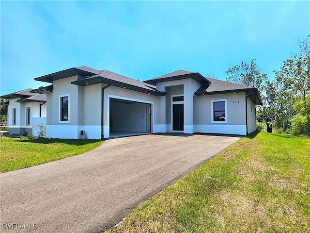prairie-style home featuring aphalt driveway, an attached garage, stucco siding, and a front lawn