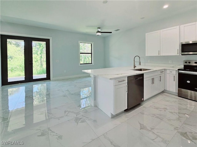 kitchen with white cabinets, appliances with stainless steel finishes, marble finish floor, a sink, and open floor plan