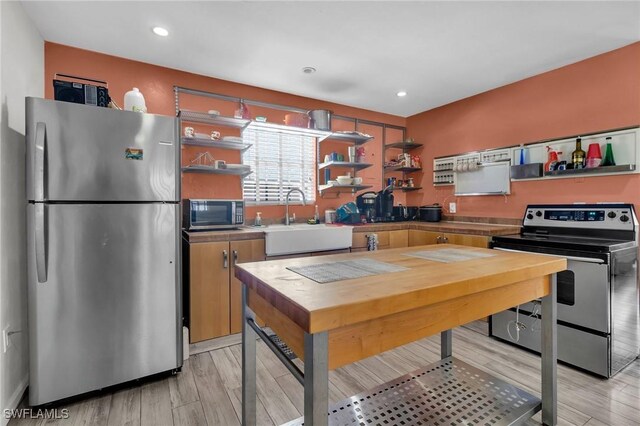 264 Mamie St, Chokoloskee, FL 34138 - kitchen with open shelves, stainless steel appliances, a sink, and light wood-style floors
