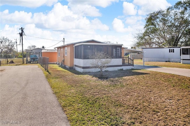 264 Mamie St, Chokoloskee, FL 34138 - view of front of home with aphalt driveway, a carport, a sunroom, and a front yard