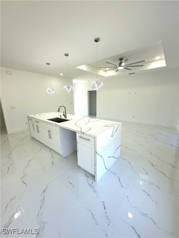 kitchen featuring ceiling fan, white cabinets, marble finish floor, a sink, and baseboards