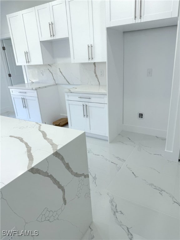 kitchen with white cabinetry, marble finish floor, and light stone counters