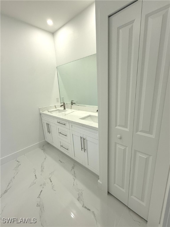 bathroom featuring a sink, baseboards, double vanity, and marble finish floor