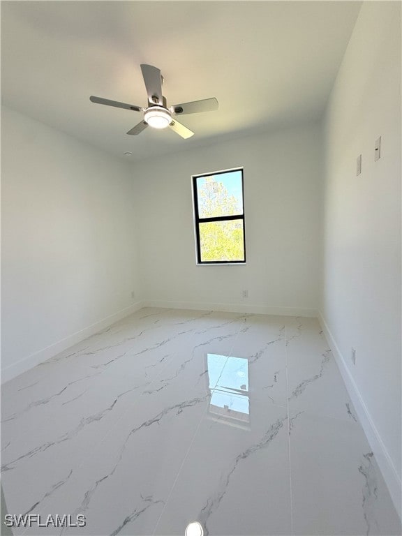empty room with marble finish floor, baseboards, and a ceiling fan