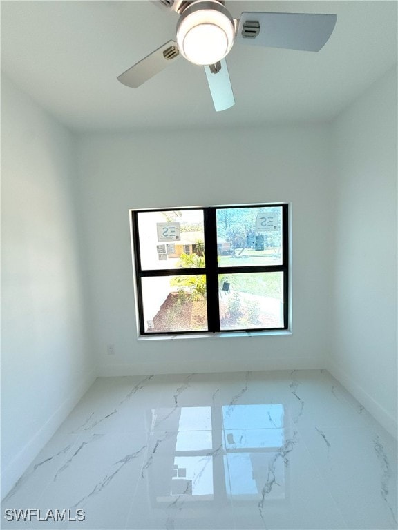 empty room with baseboards, a ceiling fan, and marble finish floor