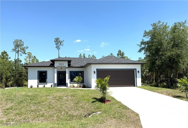 prairie-style home with concrete driveway, a front yard, a garage, and stucco siding