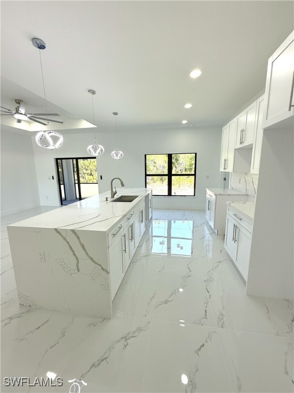 kitchen featuring a sink, recessed lighting, plenty of natural light, and light stone countertops