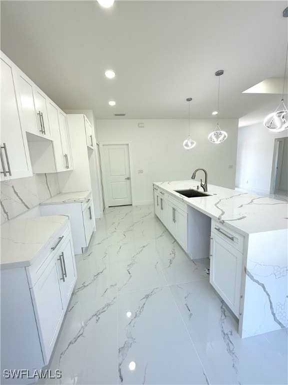 kitchen featuring a sink, recessed lighting, light stone counters, and white cabinetry