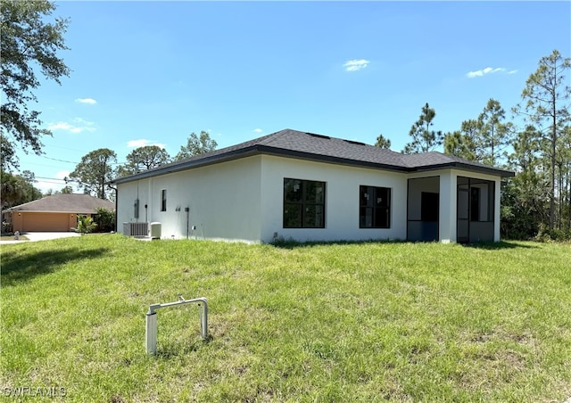 back of house with stucco siding, central AC, and a lawn