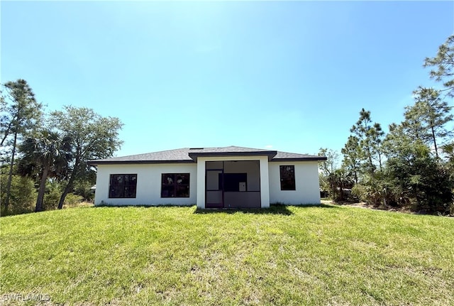 back of house featuring stucco siding and a lawn
