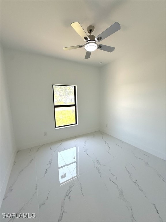unfurnished room featuring marble finish floor, baseboards, and a ceiling fan