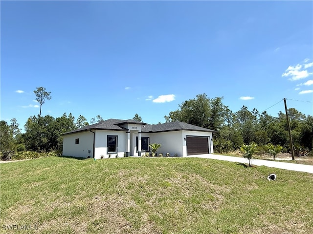 prairie-style home featuring a garage, a front yard, driveway, and stucco siding