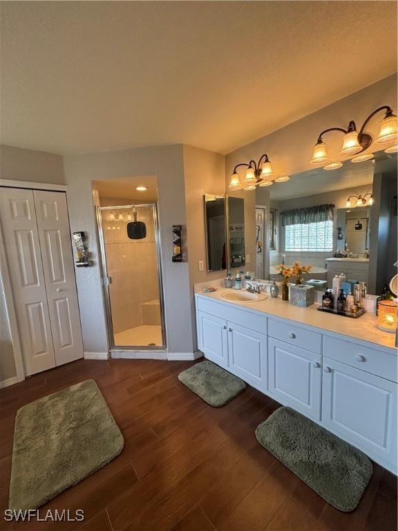 bathroom featuring a shower stall, vanity, baseboards, and wood finished floors