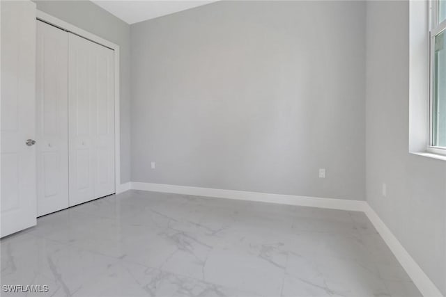 4140 31st Ave NE, Naples, FL 34120 - unfurnished bedroom with baseboards, marble finish floor, and a closet