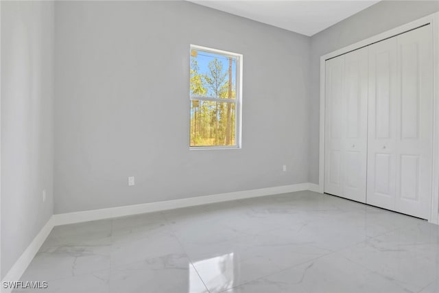 4140 31st Ave NE, Naples, FL 34120 - unfurnished bedroom featuring baseboards, marble finish floor, and a closet