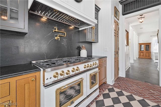 8241 Main St, Bokeelia, FL 33922 - kitchen with double oven range, custom exhaust hood, tasteful backsplash, glass insert cabinets, and dark countertops