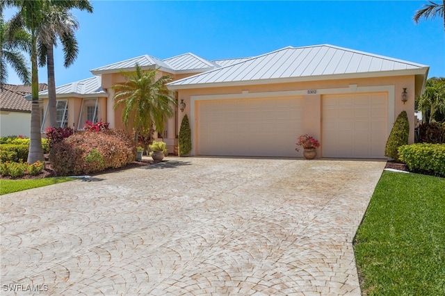 5302 SW 27th Pl, Cape Coral, FL 33914 - view of front of home with a standing seam roof, an attached garage, driveway, metal roof, and stucco siding