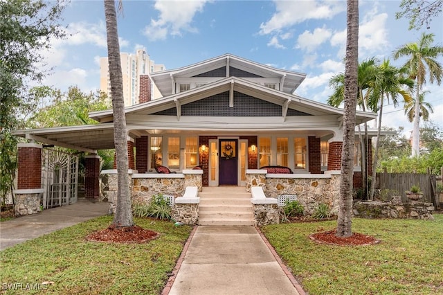 craftsman-style house featuring a porch, fence, a front yard, and brick siding