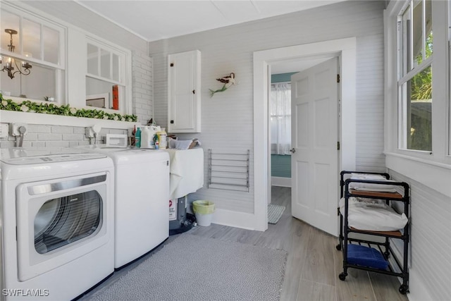 laundry area with washing machine and dryer, light wood-style flooring, a notable chandelier, and cabinet space