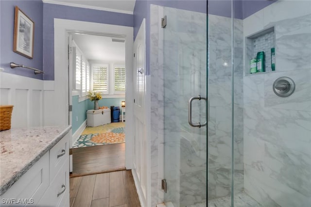 full bath featuring wood finished floors, a marble finish shower, and vanity