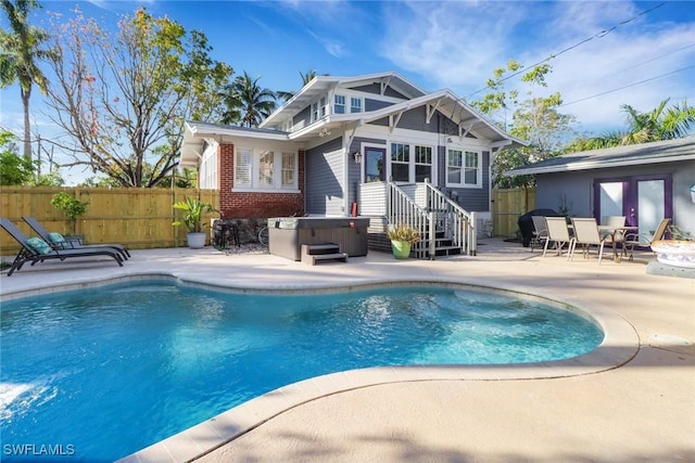 rear view of property with fence, a hot tub, a patio, a fenced in pool, and brick siding