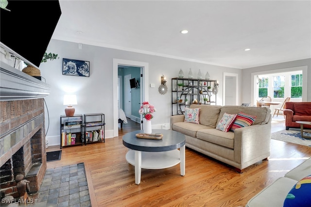 living room featuring recessed lighting, light wood-style flooring, a brick fireplace, and baseboards