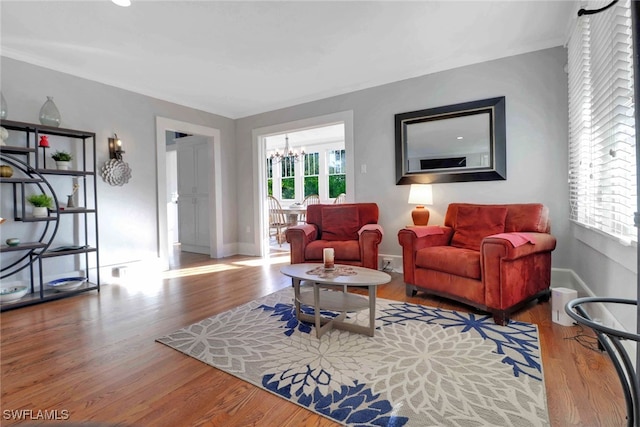 living area with baseboards, wood finished floors, and an inviting chandelier