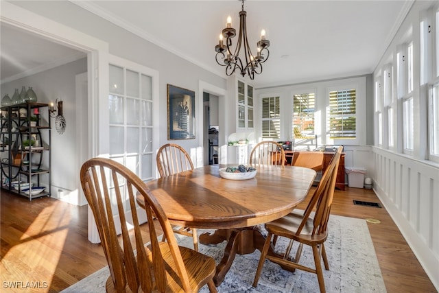 dining room featuring wood finished floors, visible vents, a notable chandelier, and ornamental molding