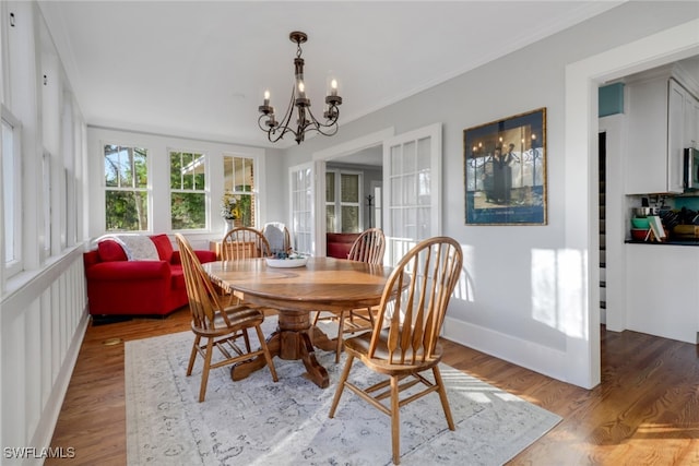 dining area featuring crown molding, baseboards, a notable chandelier, and wood finished floors