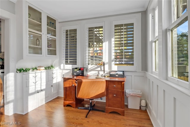 home office with light wood-style flooring, a decorative wall, and a healthy amount of sunlight