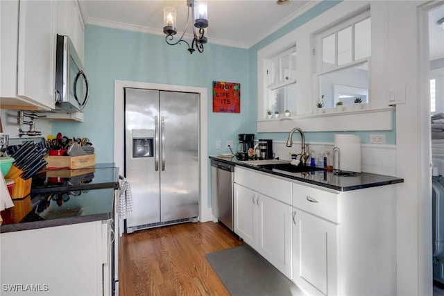 kitchen with dark countertops, appliances with stainless steel finishes, crown molding, and a sink