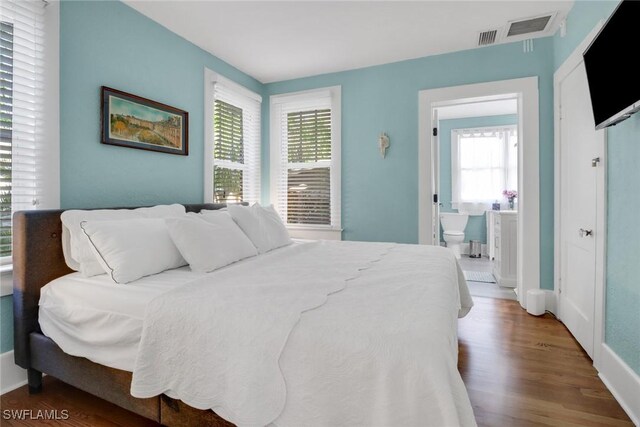 bedroom with baseboards, wood finished floors, visible vents, and multiple windows