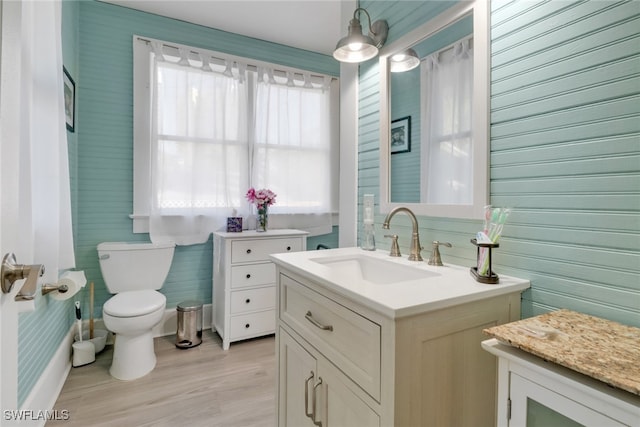 bathroom featuring baseboards, wood finished floors, vanity, and toilet