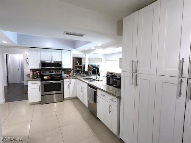9170 24th Pl, Sunrise, FL 33322 - kitchen featuring a tray ceiling, white cabinets, appliances with stainless steel finishes, light stone counters, and a sink