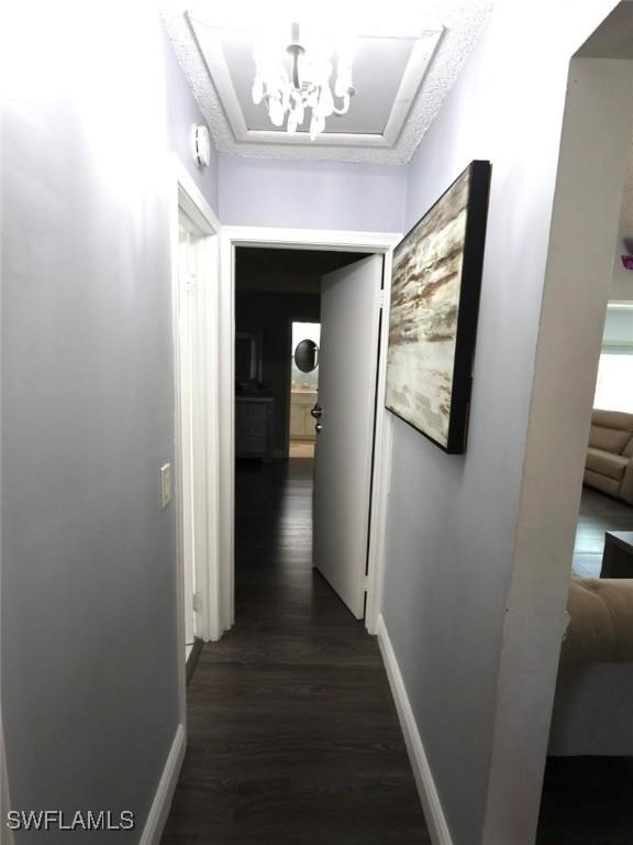 9170 24th Pl, Sunrise, FL 33322 - hall with baseboards, a notable chandelier, and dark wood-style floors